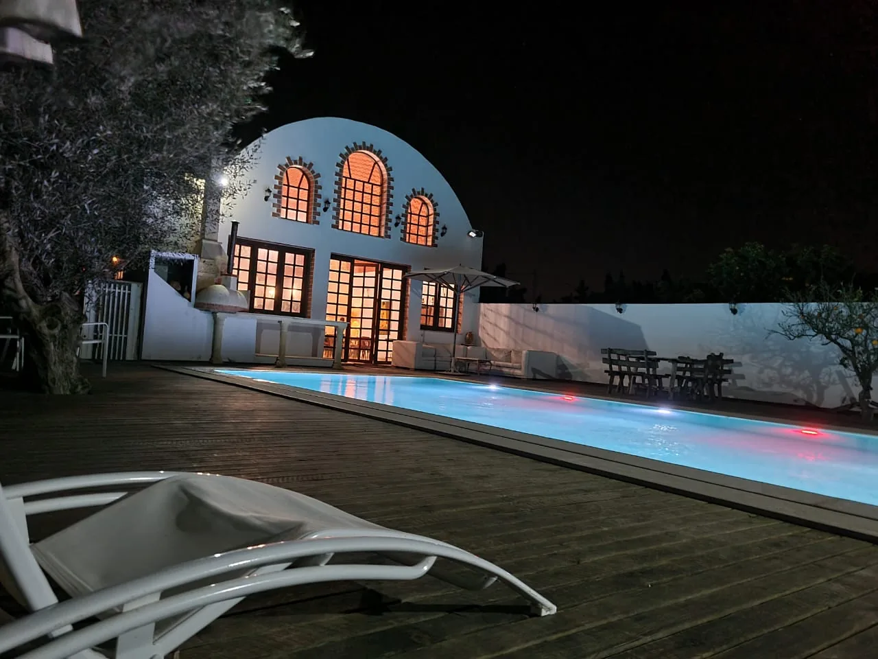 Lit pool and arched façade of the Trinity Soul retreat property in the evening